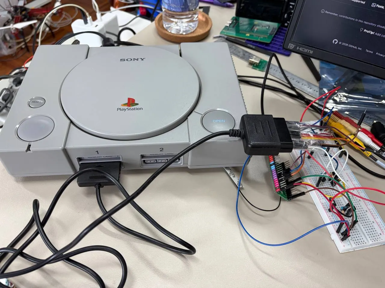 PlayStation on a bench with a controller cable wired to an ESP32 on a breadboard