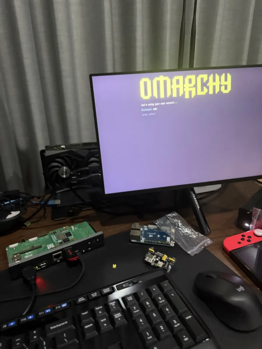 Omarchy boot screen on a monitor, with a Raspberry Pi CM5 on the desk